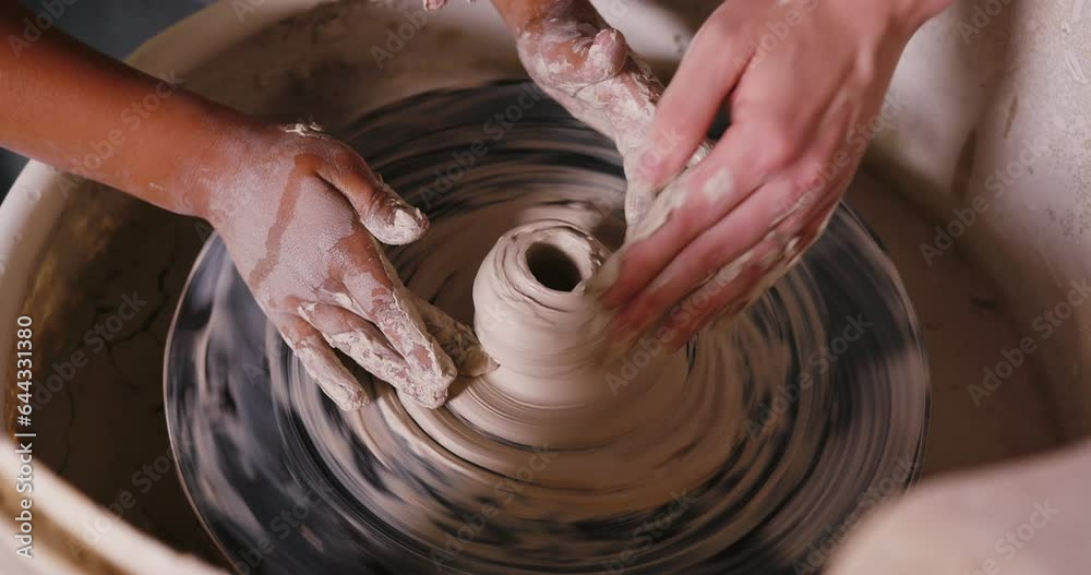 Child and adult hands sculpt clay vase on potter wheel Child and adult hands sculpt clay vase on potter wheel