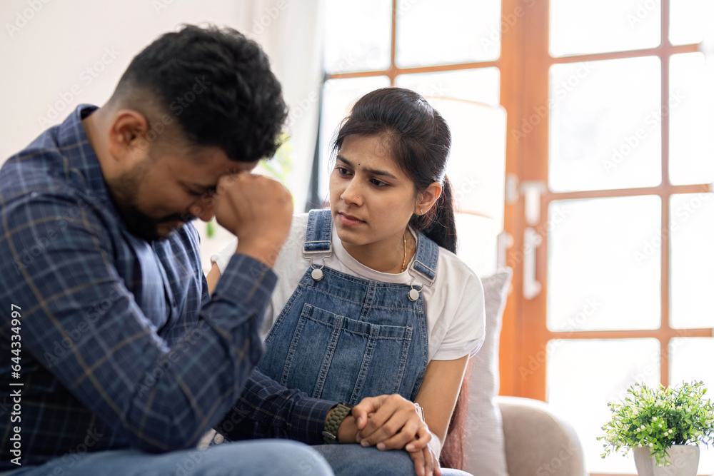 A young woman encourages and holds the hand of her worried husband. is having a hard time making some decisions. A young woman encourages and holds the hand of her worried husband. is having a hard time making some decisions.