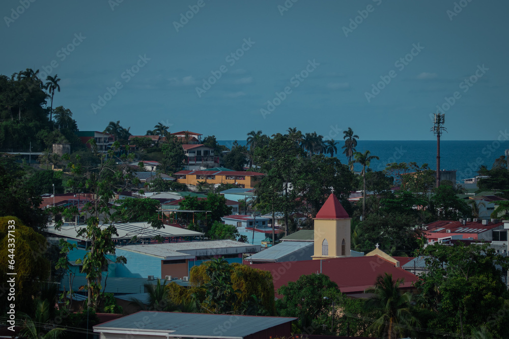 Panorama of the city of Limon in Costarica, view from the hill above the city, church and palm trees in the background with visible carribean sea.