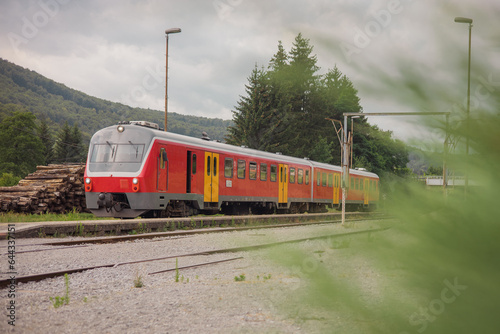 Old type of diesel train in rural station of Trebnje, Slovenia standing at a narrow platform. Look towards the train through the grass.
