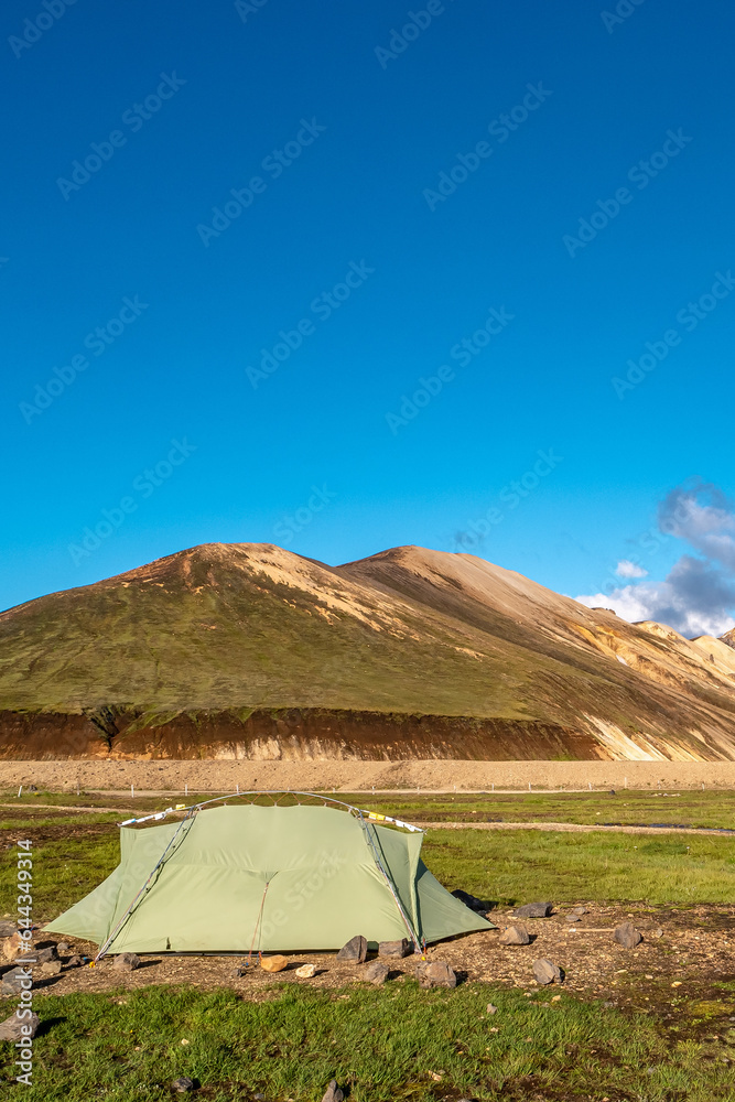 Landmannalaugar, Iceland. Cover page with a tent, blue sky and copy space. Camping site, Icelandic landscape of colorful rainbow volcanic Landmannalaugar mountains at Laugavegur hiking trail