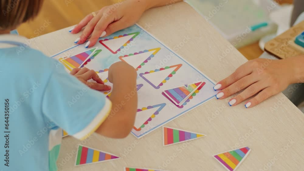 A dedicated woman, a preschool teacher, guides boys and girls at the colorful table, making education a fun and happy journey. A dedicated woman, a preschool teacher, guides boys and girls at the colorful table, making education a fun and happy journey.