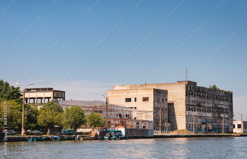 Photo of a building undergoing renovation with a serene body of water in the foreground Danube Delta birds wild life