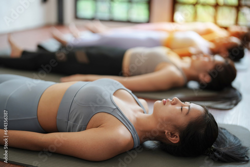 Group of yoga women are in final resting pose to relax mind and body before ending classes.