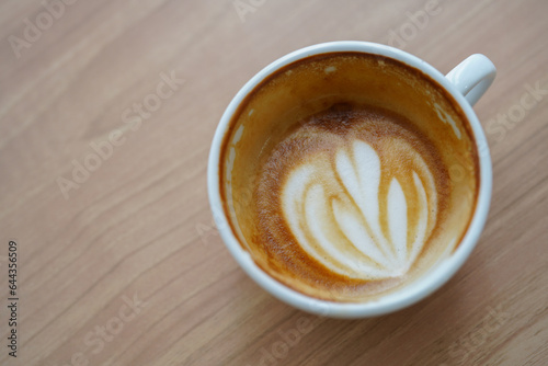 Half cup of hot latte art in heart shaped after drink on wooden table background. Copy space.