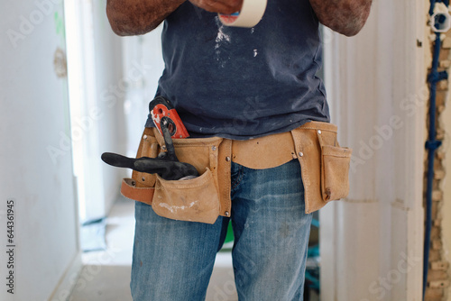 Construction worker wearing tool belt standing at site
