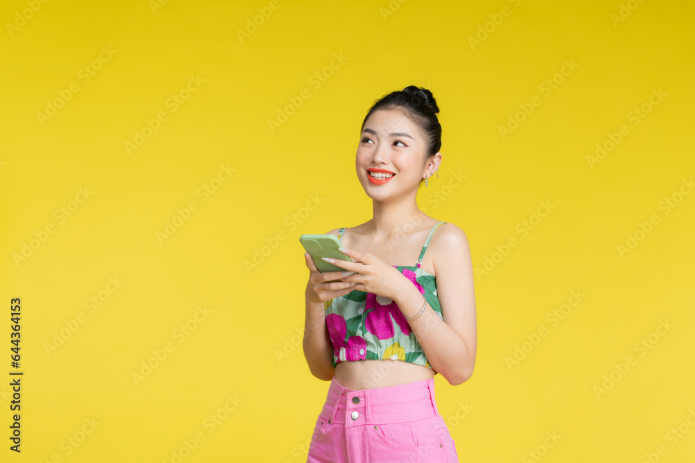 Young Asian woman over isolated yellow background sending a message with the mobile Young Asian woman over isolated yellow background sending a message with the mobile