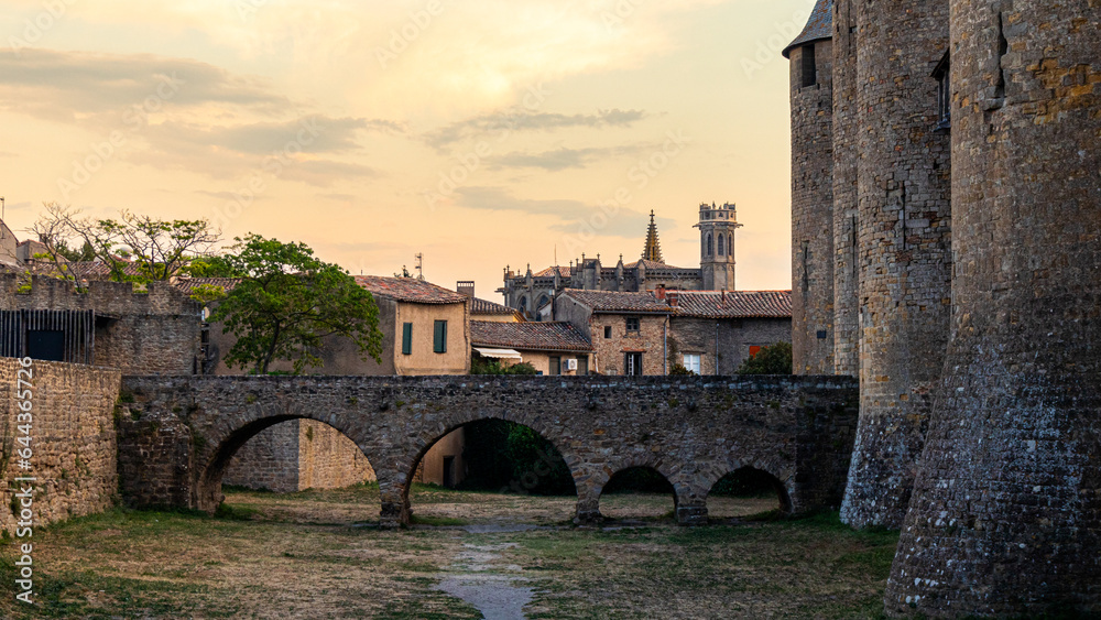 Old romanic bridge and aquaduct connecting to a castle with a church in the back and misterious sky