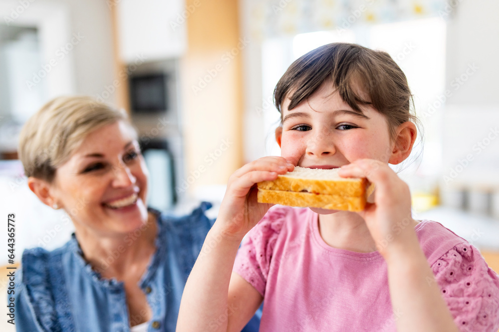 Girl having sandwich by mother at home Girl having sandwich by mother at home