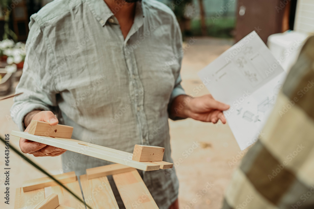 Man holding instruction manual and wooden plank Man holding instruction manual and wooden plank