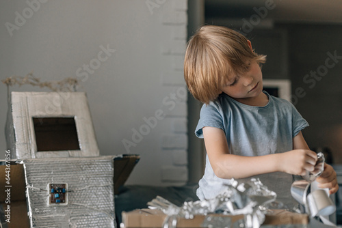 Focused boy with silver foil paper making astronaut costume photo