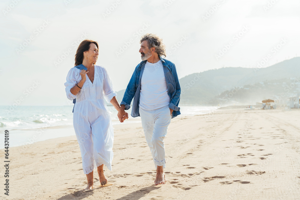 Happy senior couple holding hands and walking at beach Happy senior couple holding hands and walking at beach