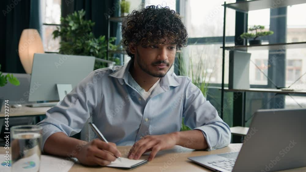 Arabian latino guy male businessman Indian man worker employer writer manager studying write business notes on office desk writing tasks ideas at paper notebook work schedule look at laptop computer Arabian latino guy male businessman Indian man worker employer writer manager studying write business notes on office desk writing tasks ideas at paper notebook work schedule look at laptop computer
