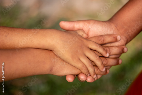Three boys join hands together and put their hands on each other to form a partnership