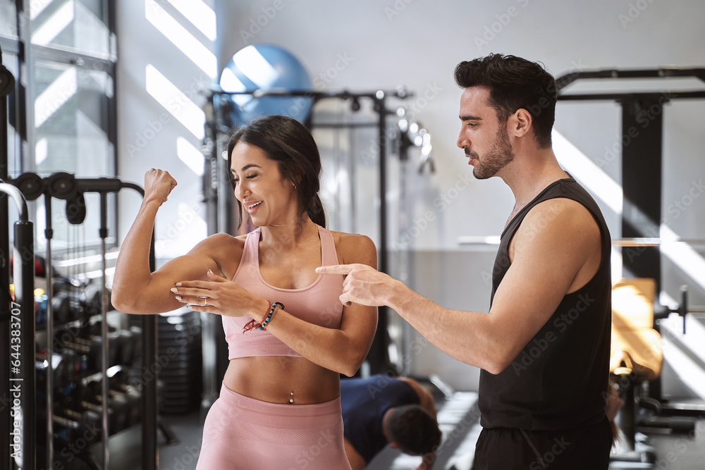 Fitness woman showing her muscle to her personal trainer after working out in the gym. Sports concept. Fitness woman showing her muscle to her personal trainer after working out in the gym. Sports concept.