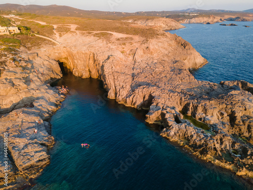 View from a drone at sunset on a bay with blue water. Cala Grotta, Sardinia Italy