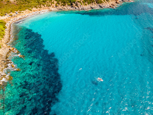 Small boat near the beach with turquoise clear water. The most beautiful sea in Italy. Sardinia Italy