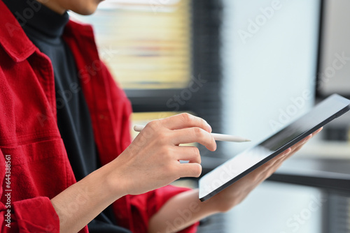 Closeup view of modern business man holding paper cup and using digital tablet at office desk
