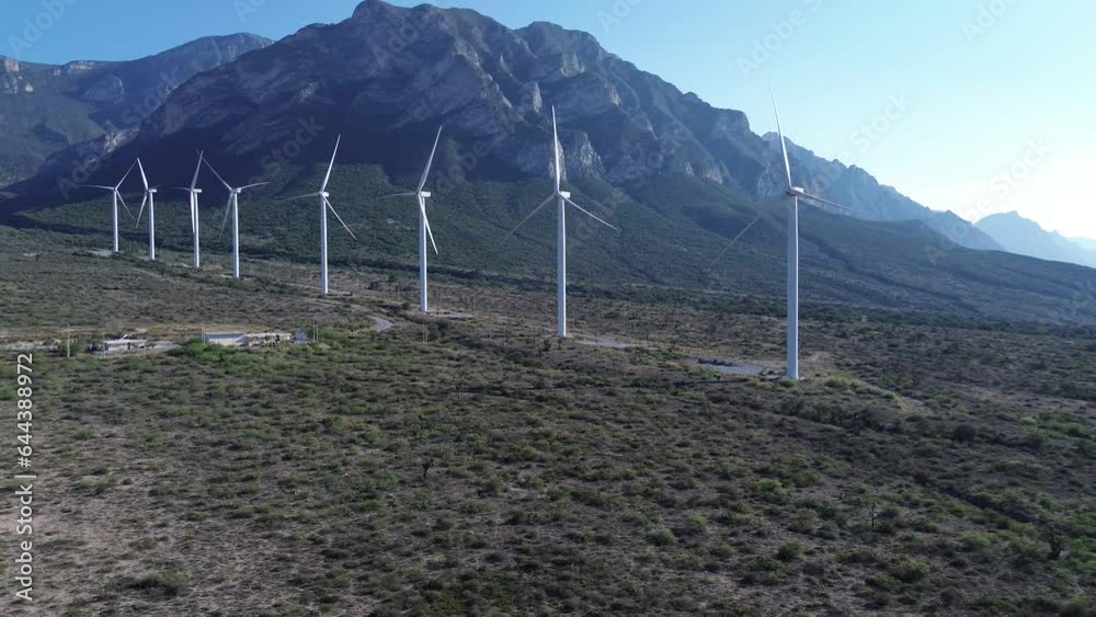 Planta eólica de luz que se pueden apreciar varios molinos y atrás de ellos una montaña de paisaje 
