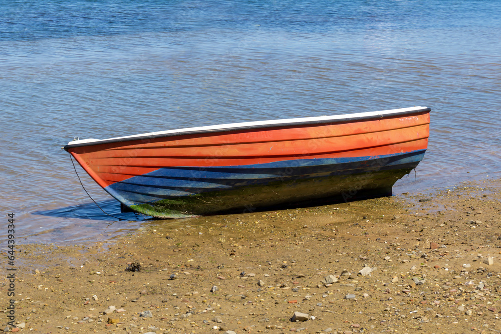 Little red and blue wooden boat, with no one on board, on the shore of the blue sea
Little red and blue wooden boat, with no one on board, on the shore of the blue sea