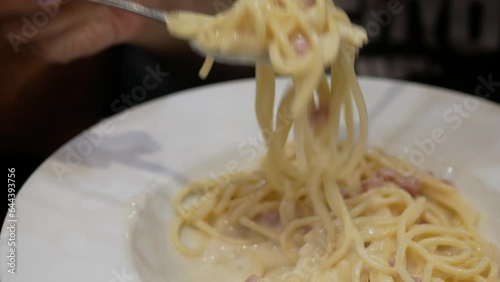 using fork and spoon to eat fresh homemade spaghetti white sauce pasta at home for dinner time, italian cuisine food dinning in homemade style photo
