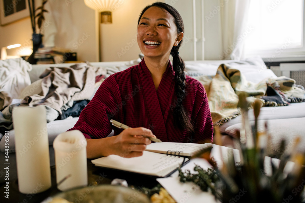 Happy young woman with book herbs at table