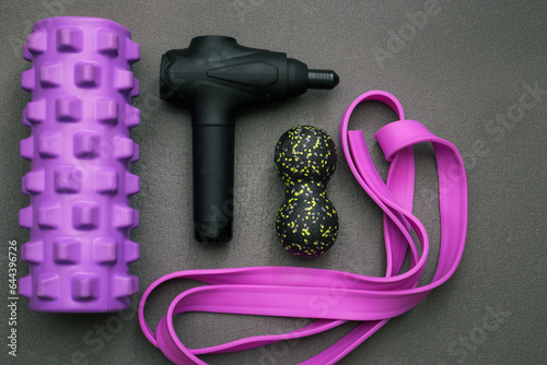 Rehabilitation sports medicine concept. Percussion Massage Gun, Resistance band, Myofascial foam rollers on the yoga mat.