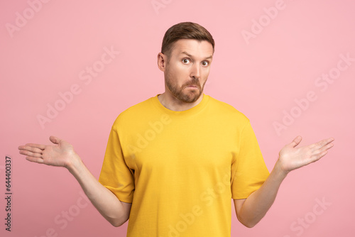Obraz na plátně Puzzled stunned confused man gesturing hands sign do not know spreading arms by sides, isolated background