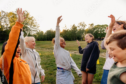Carefree kids dancing with hand raised in playground at summer camp
