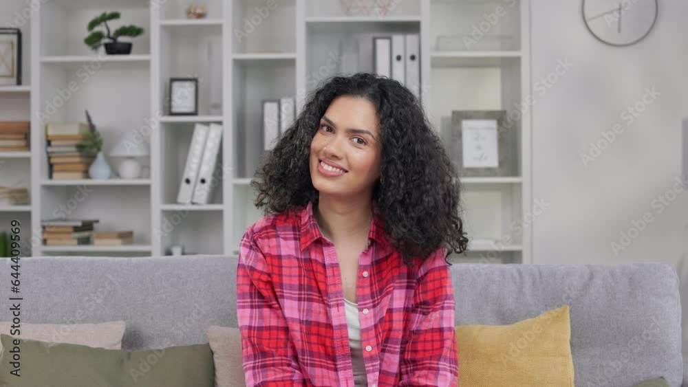 Portrait of delightful african american adult with dark curly hair posing on camera and happily smiling. Cheerful female wearing casual clothing spending pastime at home. Portrait of delightful african american adult with dark curly hair posing on camera and happily smiling. Cheerful female wearing casual clothing spending pastime at home.