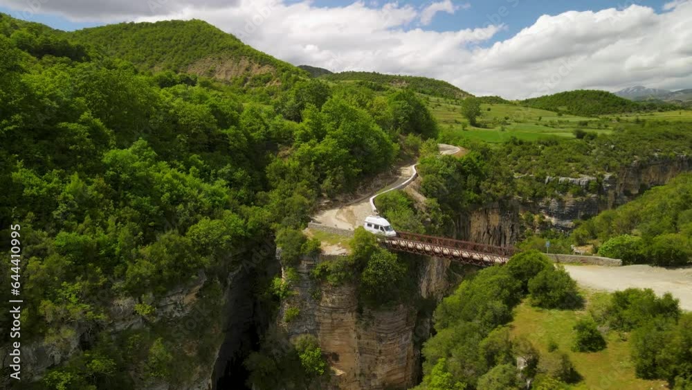 aerial perspective of a sunny day as a travel caravan crosses a bridge over Osumi Canyon in Albania. aerial perspective of a sunny day as a travel caravan crosses a bridge over Osumi Canyon in Albania.