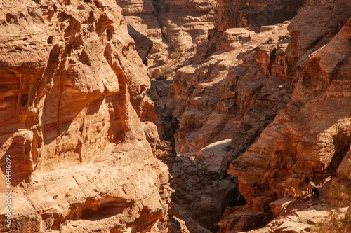 Jordan, Petra, Narrow road to Ad Deir monastery. Blurred background. Selective focus. Mountain landscapes with steep abysses. Road between rocks going up. Rocky rocks of red, pink and orange tones.