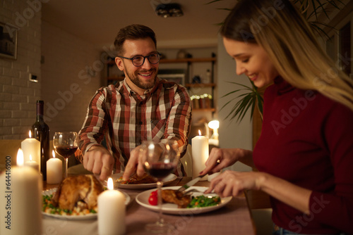 Beautiful couple having romantic dinner with candles and red wine at home