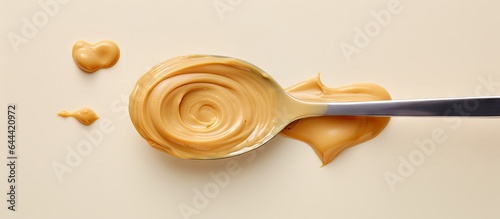 Peanut butter on a spoon against isolated pastel background Copy space American morning delight photo