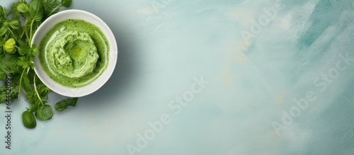 Top view of a bowl of delicious arugula pesto and ingredients on a isolated pastel background Copy space