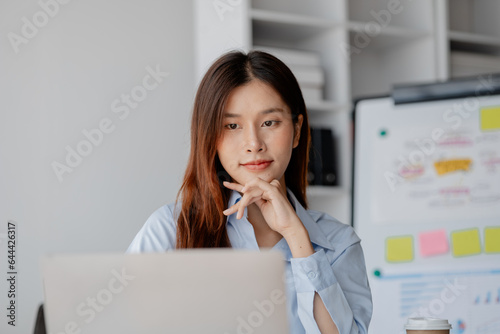 Asian woman sitting in startup company office, marketing analyzing and planning marketing for company growth, sales management. Businessman concept, marketing planning.