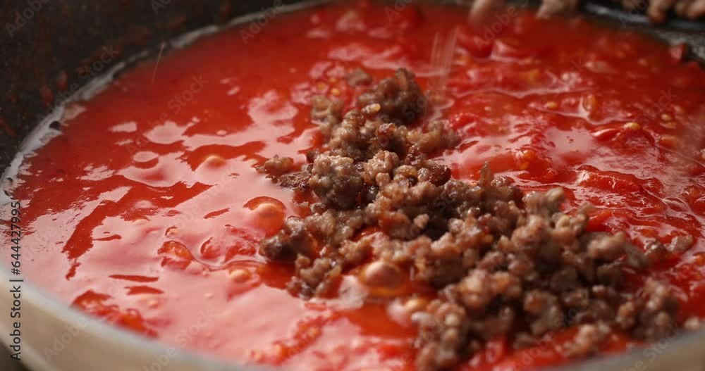 Adding fried minced meat to tomato sauce in a pan. Cooking bolognese sauce. Food preparation in the kitchen. A series of footage to visualize the recipe. Adding fried minced meat to tomato sauce in a pan. Cooking bolognese sauce. Food preparation in the kitchen. A series of footage to visualize the recipe.