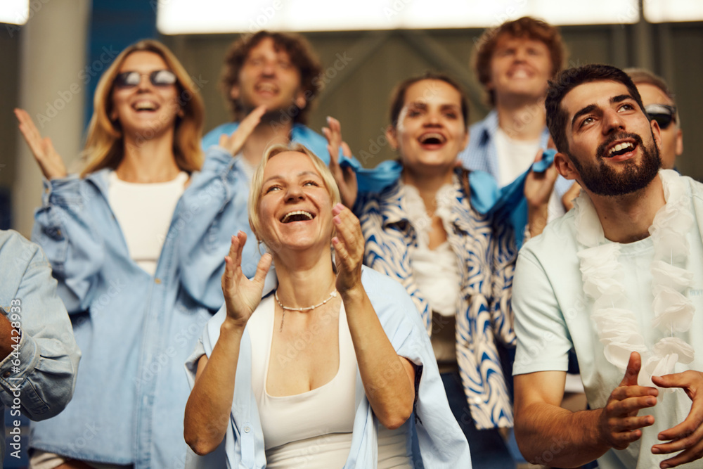 Feeling happy. Men and women, football fans cheering up favourite team in stadium during game. Winning. Concept of sport, world cup, team, event and competition, emotions, championship, betting Feeling happy. Men and women, football fans cheering up favourite team in stadium during game. Winning. Concept of sport, world cup, team, event and competition, emotions, championship, betting