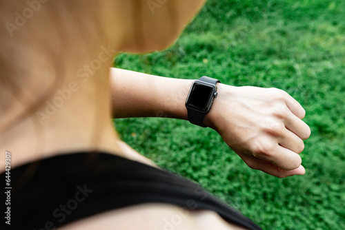 Young woman looking at fitness bracelet and tracking cardio workout results.