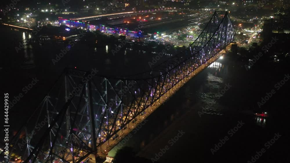Aerial view of architectural landmark Howrah bridge or Rabindra Setu over the Hooghly River at night in Kolkata, West Bengal, India.