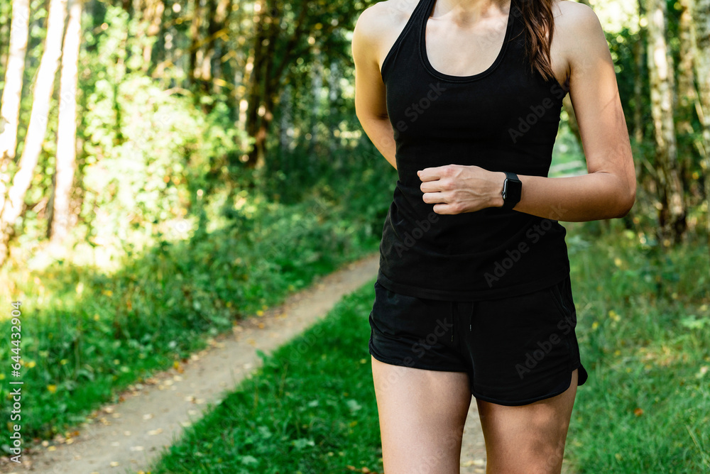 Young fitness woman in black sportwears running at morning forest trail. Young fitness woman in black sportwears running at morning forest trail.