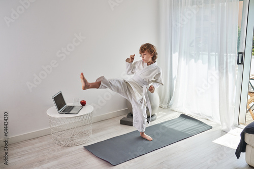 Barefoot boy practicing kicks a home