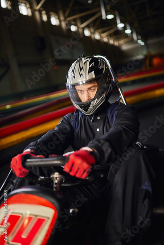 concentrated racer in helmet driving go kart car on indoor circuit, motorsport competition concept