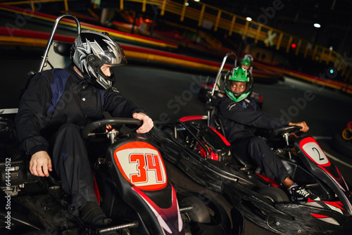 multiethnic competitors driving go kart on indoor circuit, speed racing and motorsport © LIGHTFIELD STUDIOS