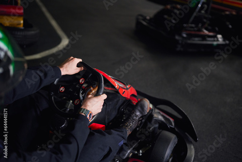 racer in helmet and sportswear driving go kart on indoor circuit, steering wheel, adrenaline concept © LIGHTFIELD STUDIOS