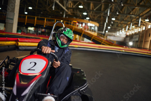 go cart speed drive, african american driver in helmet on circuit, karting motorsport concept