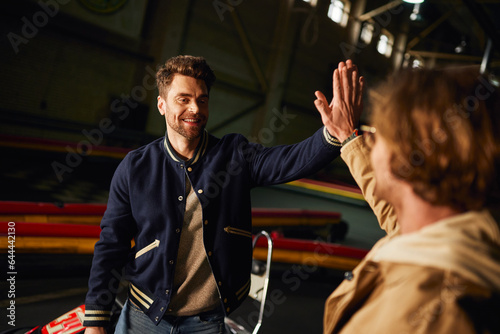 excited male friends giving high five to each other inside of karting racing track, teamwork and win © LIGHTFIELD STUDIOS