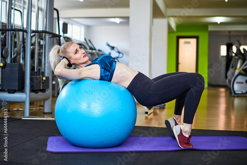 Beautiful woman is doing exercises in a fitness room with ball