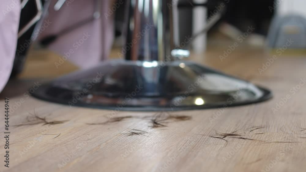 Close-up floor in beauty salon with hair falling down in slow motion. Closeup spa parlor interior in the process of haircut styling