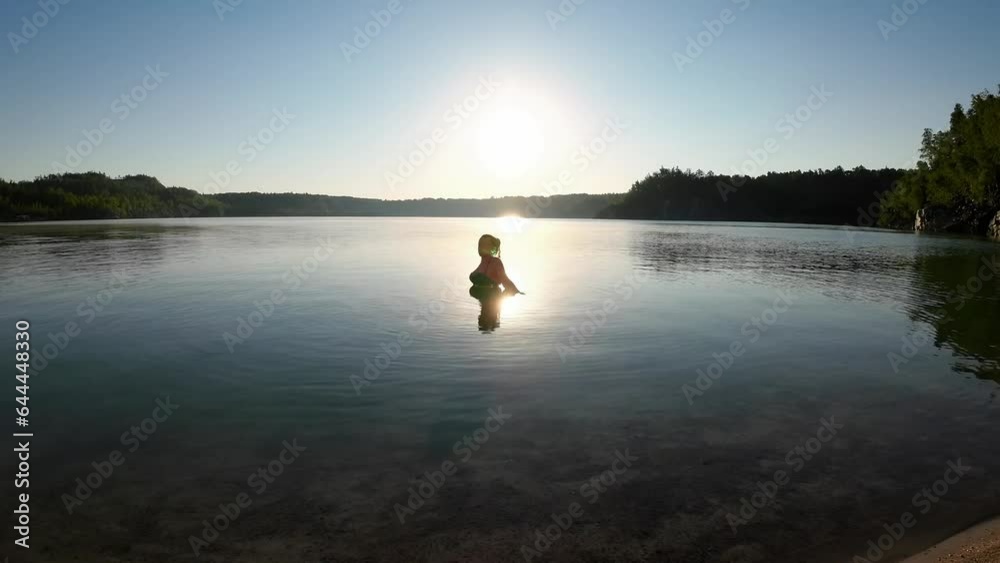 A woman raises a splash of water while swimming in a scenic lake A woman raises a splash of water while swimming in a scenic lake